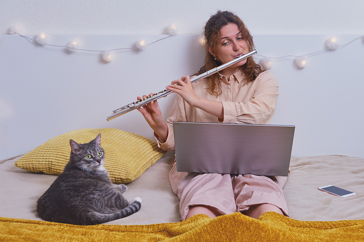 Gato escuchando a una mujer tocando la flauta